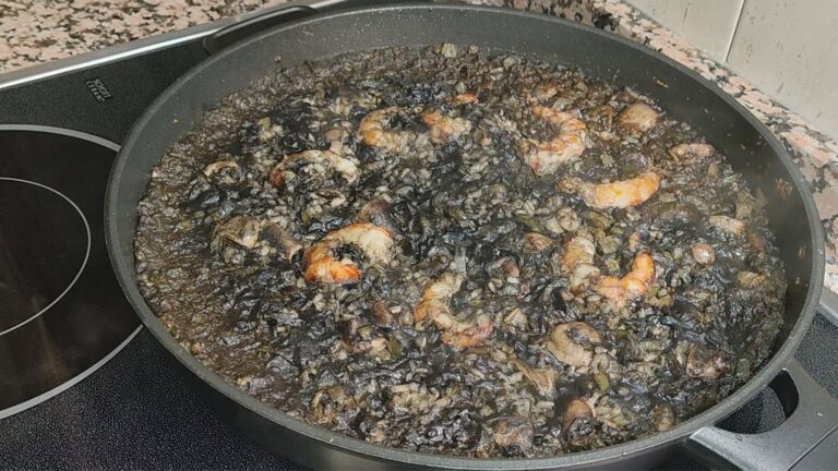 Arroz negro con marisco cocinado en sartén, con gambas y tinta de calamar sobre fuego