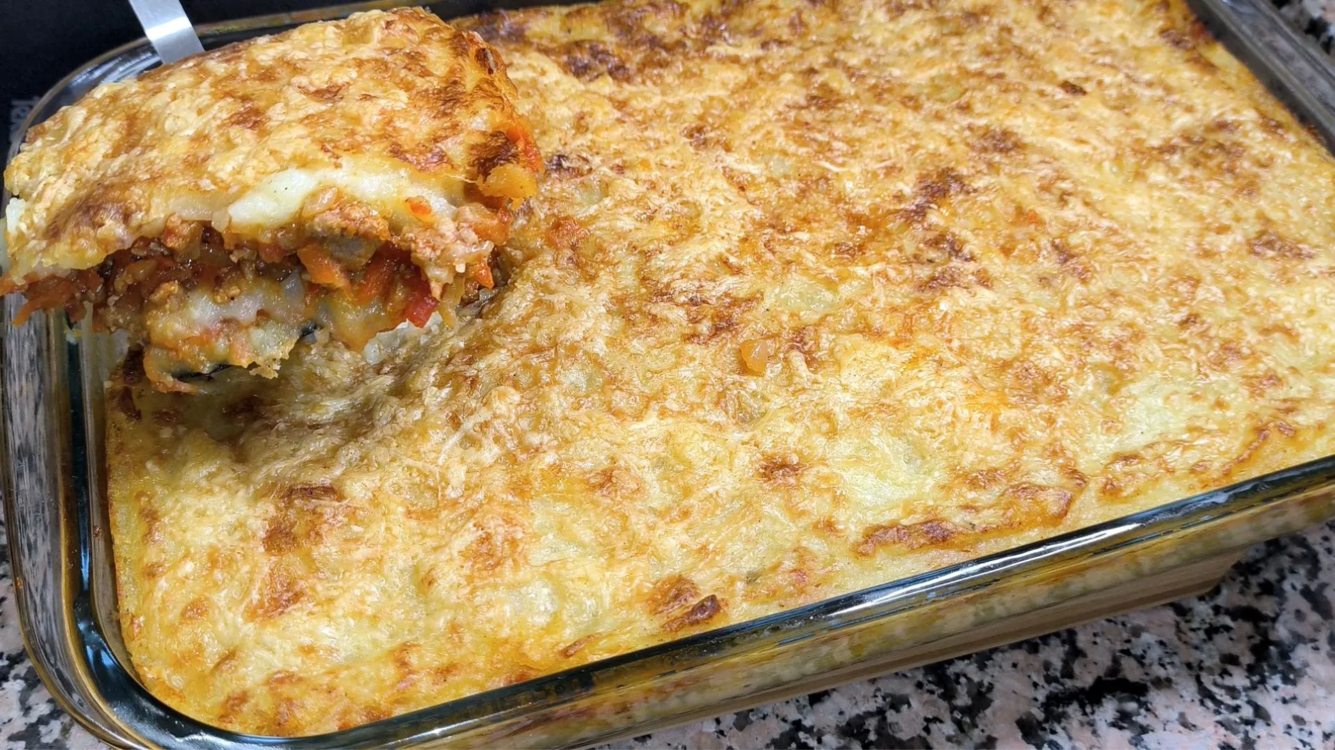 Porción de pastel de patatas con carne picada y queso gratinado en fuente de horno