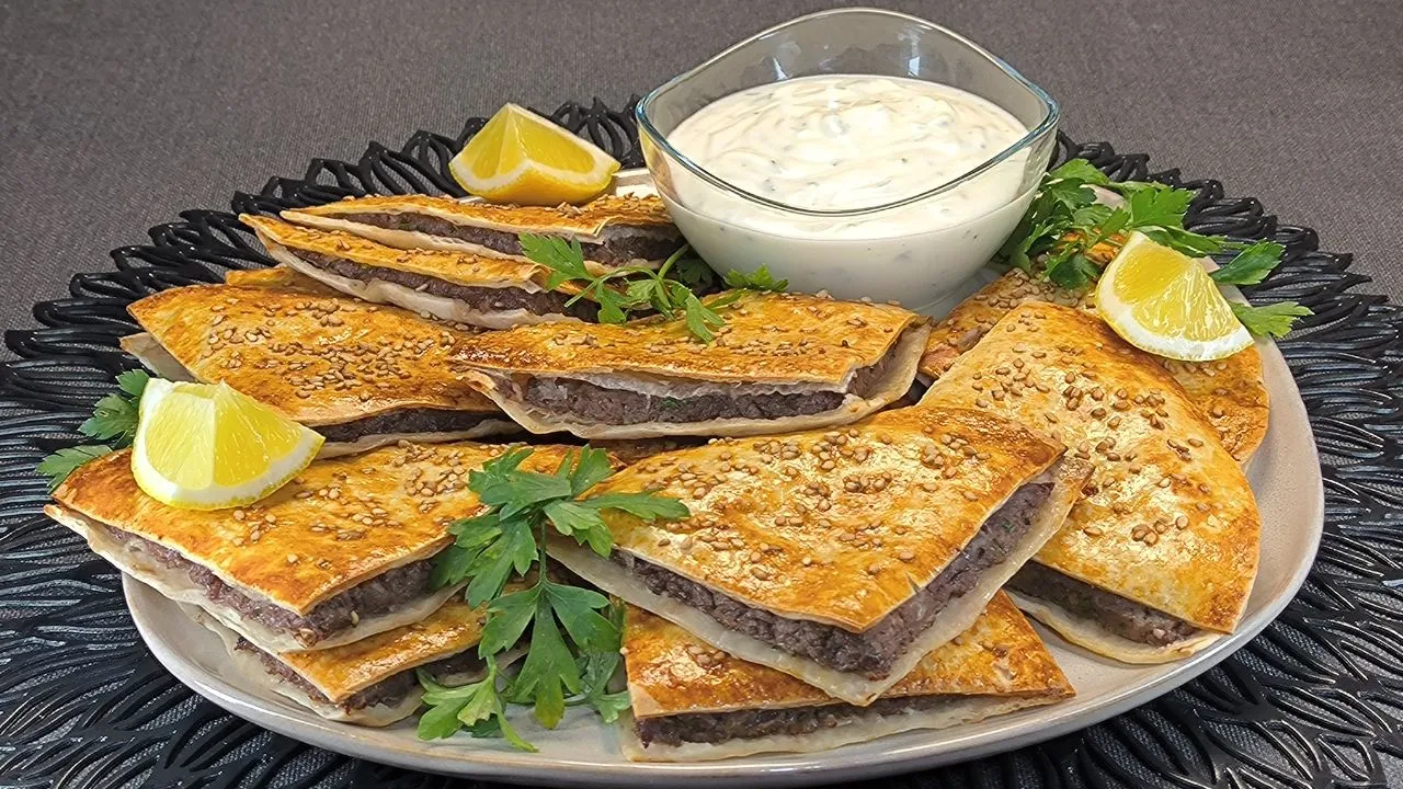 Arayes de ternera en pan pita rellenos de carne picada sazonada con semillas de sésamo doradas en freidora de aire sobre una tabla de madera.