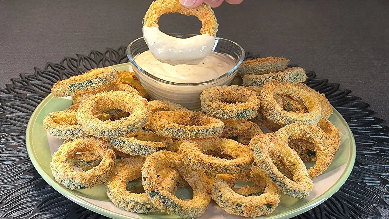 Aros de calabacín crujientes rebozados y dorados en freidora de aire servidos con salsa cremosa