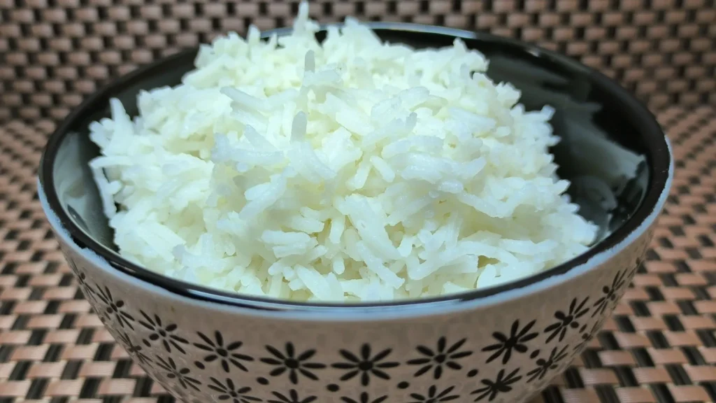 Primer plano de arroz basmati blanco de grano largo servido en un bol de cerámica rústica, mostrando una textura suelta y esponjosa ideal para guarniciones.