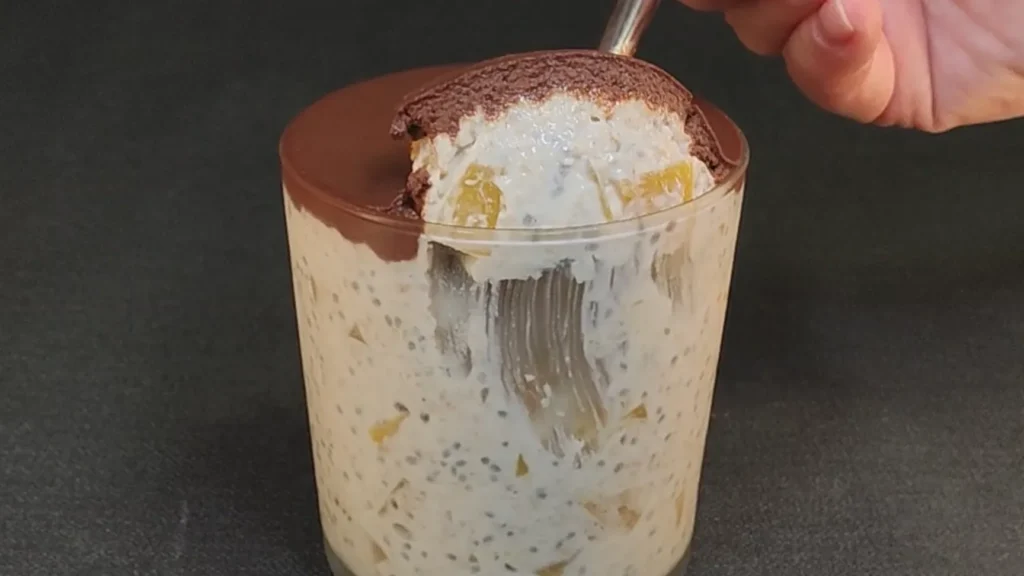 Bol de avena caliente con láminas de melocotón fresco y semillas de chía sobre una mesa de madera rústica.