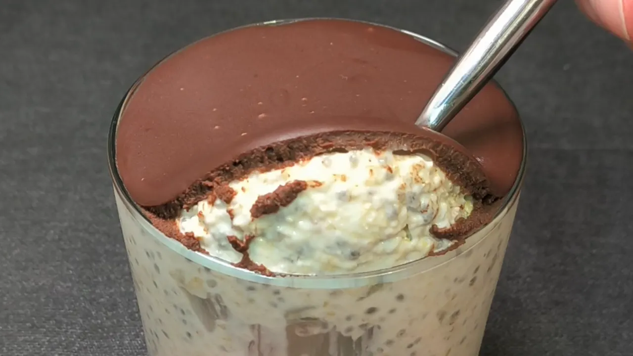 Tarro de cristal con avena reposada, trozos de piña fresca, semillas de chía y coco rallado sobre un fondo de madera.