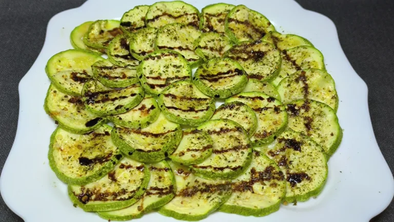 Rodajas de calabacín cocinadas al microondas con especias y un toque de aceite de oliva en un plato blanco.