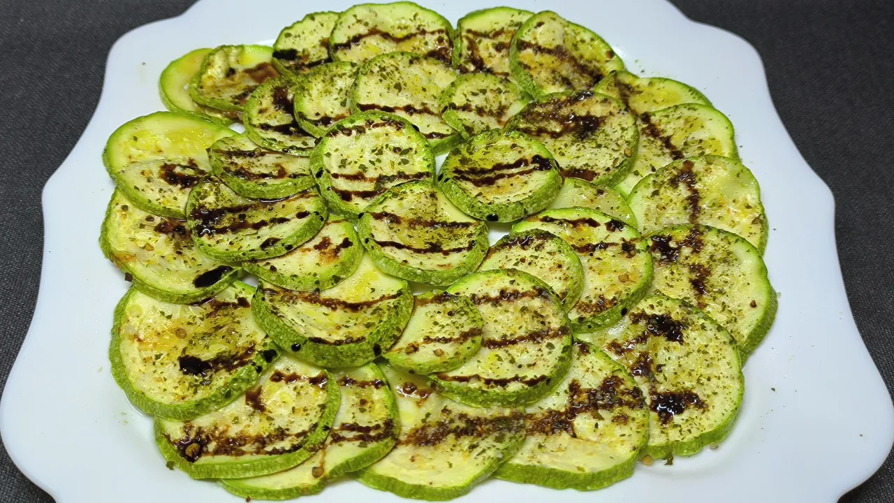 Rodajas de calabacín cocinadas al microondas con especias y un toque de aceite de oliva en un plato blanco.