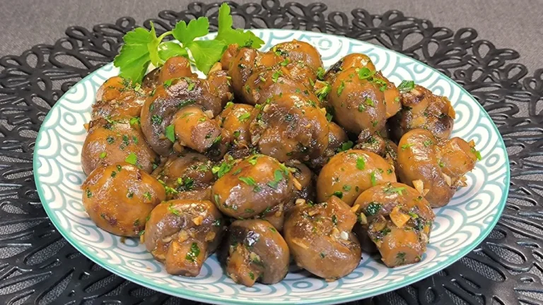 Champiñones al ajillo laminados y salteados con ajo picado, guindilla y perejil fresco en una sartén caliente.
