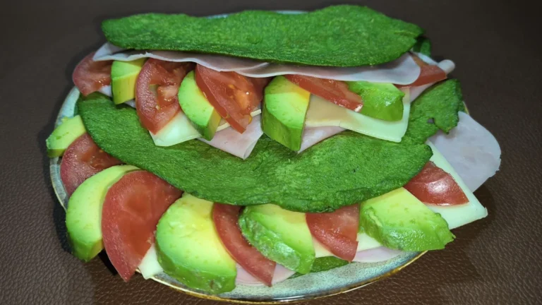 Crepes verdes de espinacas y avena rellenos de láminas de aguacate fresco y queso, servidos en un plato blanco.