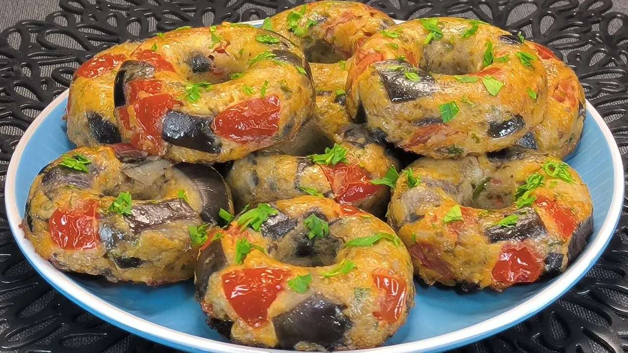 Donuts de berenjena: 1 receta increíble en freidora de aire 1 Seis donuts de berenjena rebozados y dorados con queso fundido por encima colocados en la rejilla de una freidora de aire.
