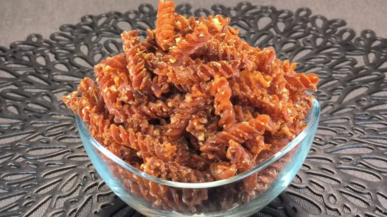 Pasta de espirales de lentejas rojas crujientes sazonadas con especias dentro de la cesta de una freidora de aire.