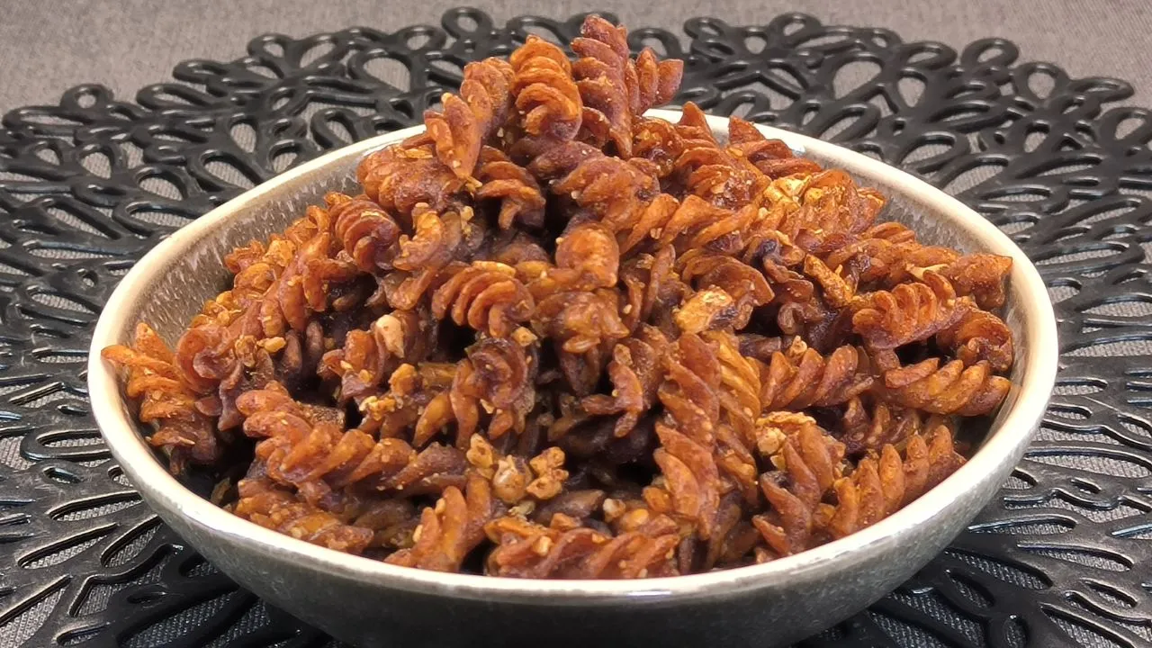 Espirales de pasta fusilli recubiertas con azúcar y canela servidas en un cuenco de cerámica rústica