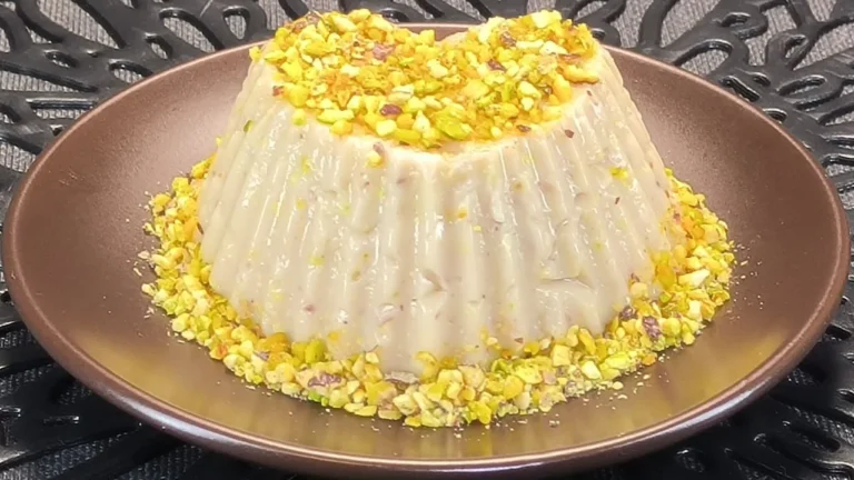 Dos flanes de pistacho desmoldados sobre platos blancos, elaborados con bebida de avena y decorados con pistachos troceados.