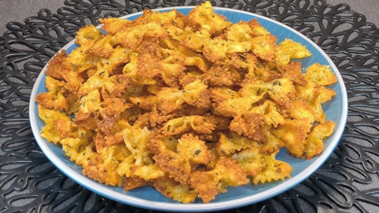 Plato de pasta farfalle o lacitos salteados con una salsa cremosa de ajo, queso parmesano rallado y perejil fresco en un cuenco oscuro.