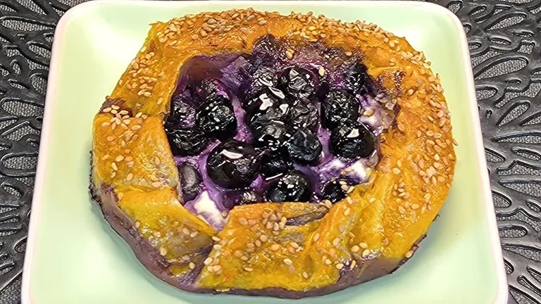 Pastel crujiente de hojas de papel de arroz relleno de queso ricotta y arándanos frescos sobre un plato de cerámica.