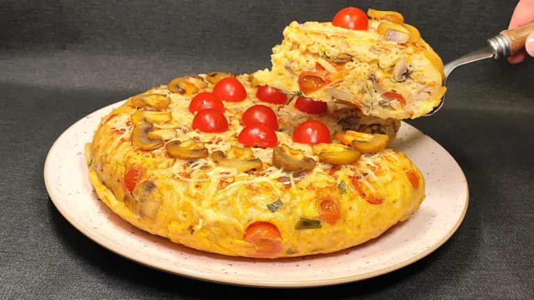 Pastel de pasta penne con champiñones y queso fundido servido directamente en una sartén negra, decorado con perejil fresco.