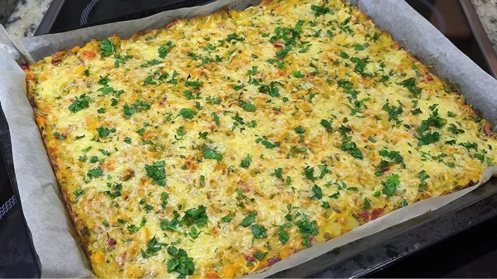 Pastel de verduras variadas gratinado en una bandeja de horno, mostrando trozos de brócoli, zanahoria y pimiento bajo una capa de queso dorado.