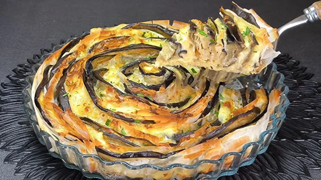 Pastel salado de berenjenas cubierto con capas crujientes y doradas de masa filo en un molde para horno