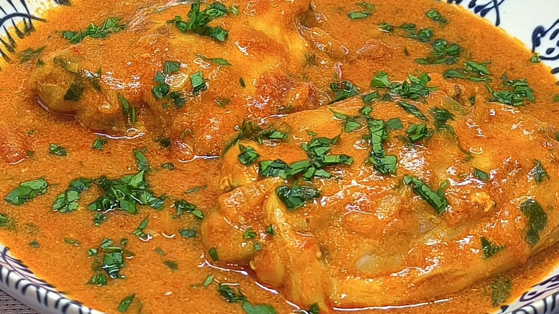 Guiso de pollo húngaro con salsa roja de pimentón y crema servido en un plato hondo con perejil fresco.