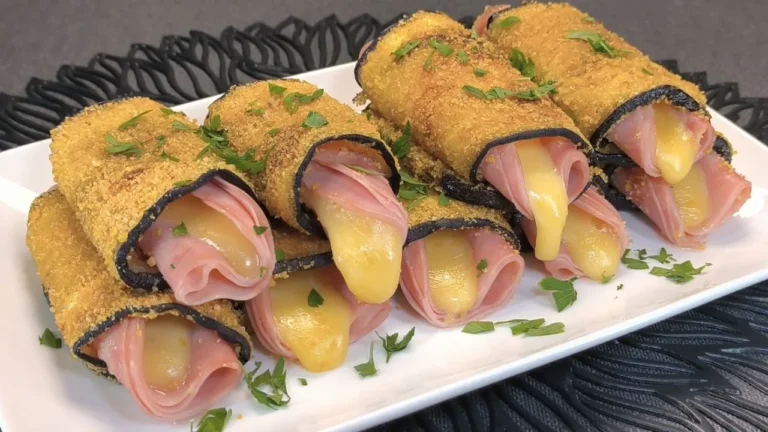 Rollitos de berenjena a la plancha rellenos de jamón york y queso fundido servidos en un plato blanco