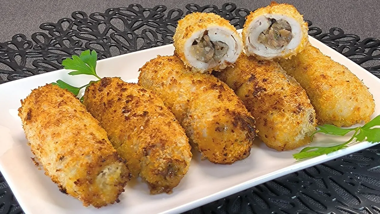 Rollitos de pechuga de pollo crujientes rebozados en panko y acompañados de champiñones, recién cocinados en freidora de aire para un acabado dorado.