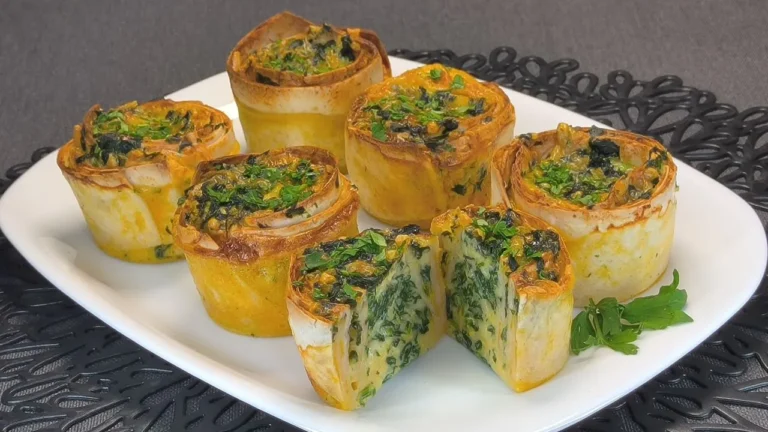 Wraps de tortilla rellenos de espinacas frescas y queso fundido cortados en mitades sobre una tabla de madera.