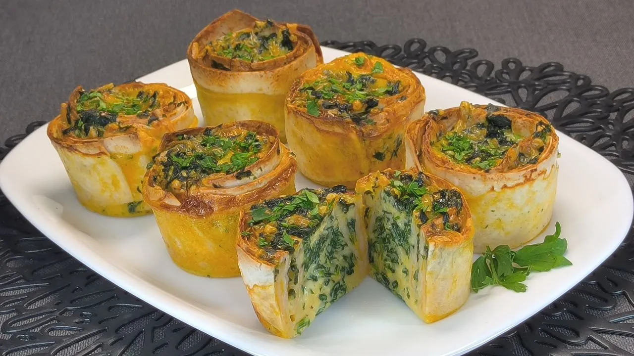 Wraps de tortilla rellenos de espinacas frescas y queso fundido cortados en mitades sobre una tabla de madera.