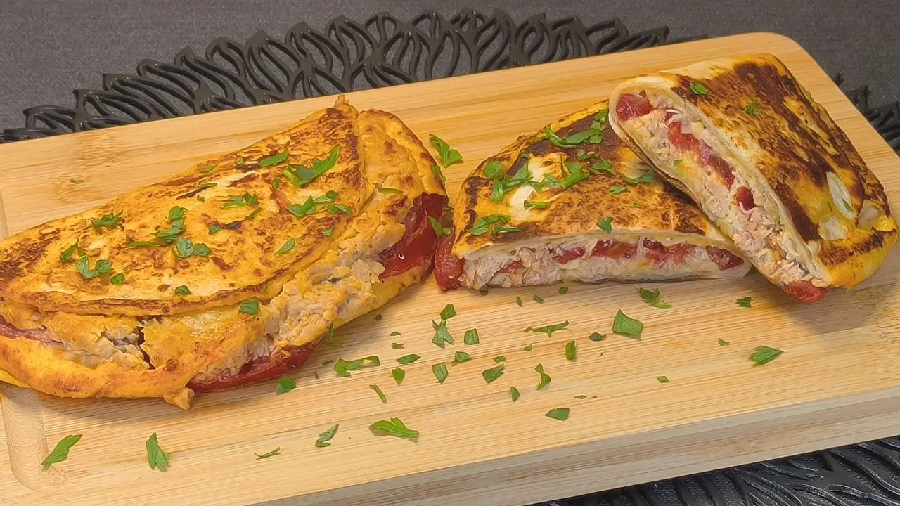 Tortilla de Trigo con Huevo y Atún: 1 Cena Exprés Deliciosa 1 tortilla de trigo con huevo y atún, queso derretido y maíz, cortada por la mitad.