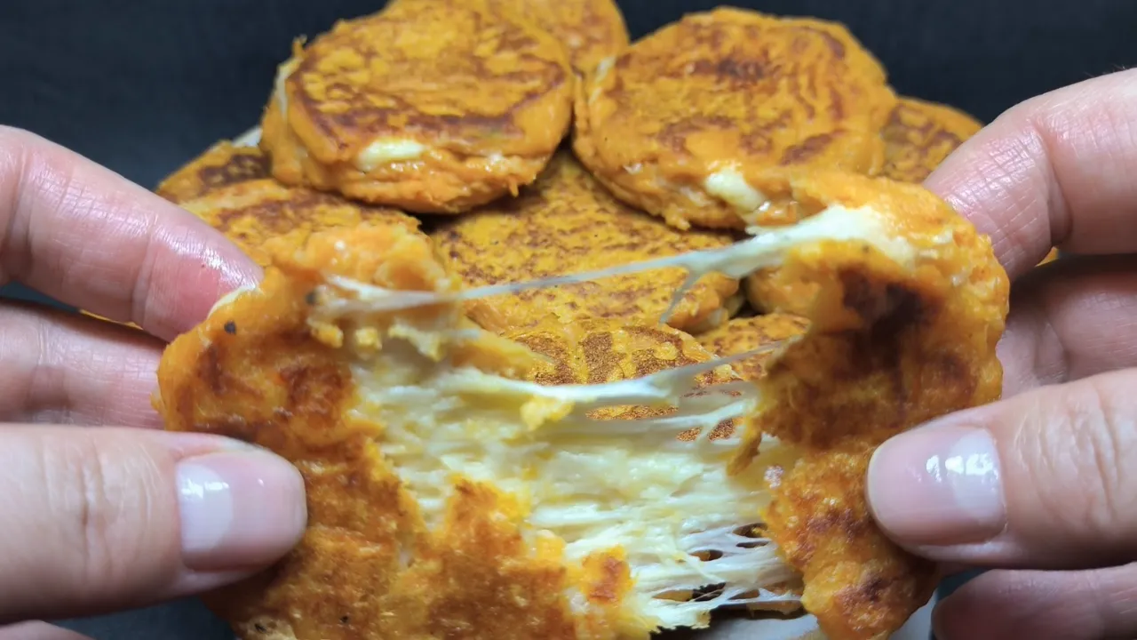 Torre de tortitas de boniato y queso doradas servidas en un plato blanco con una ramita de romero fresco.