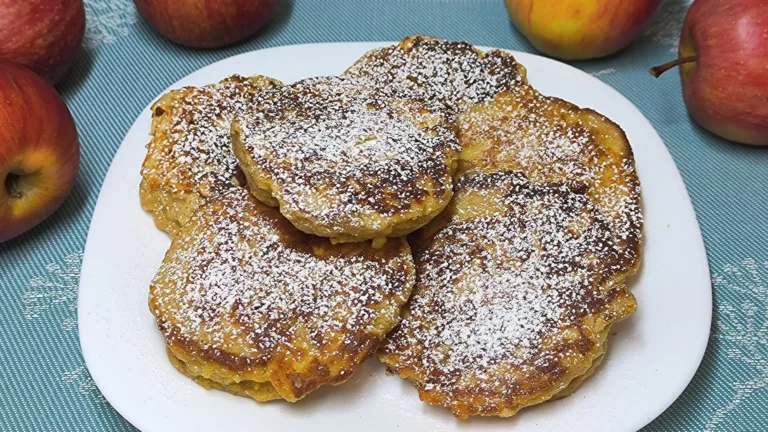 Torre de tortitas de manzana doradas y esponjosas decoradas con láminas de manzana fresca y miel.