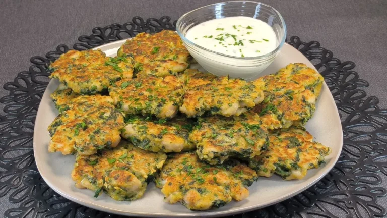 Tres tortitas de pollo con espinacas picadas dorándose en una sartén negra sobre una encimera de cocina.